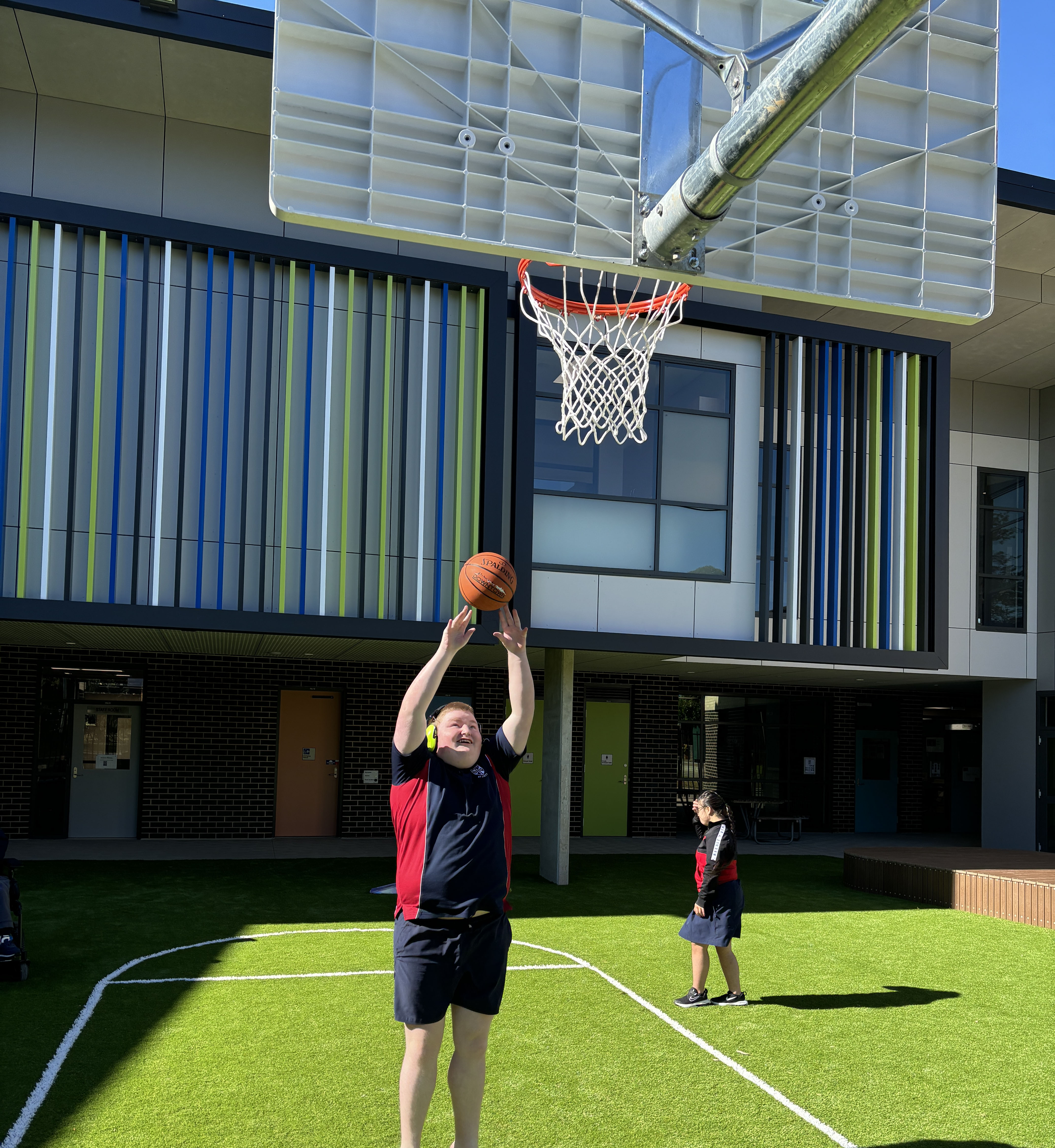 A student playing basketball in the new outdoor area at St Lucy School.