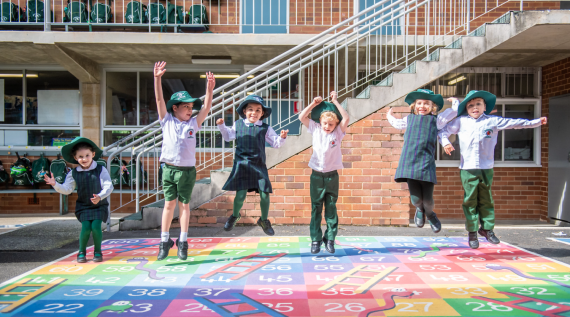 A line of school children jumping in the playground.