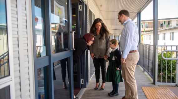 Parents dropping their child at the Catholic school classroom to meet the teacher.