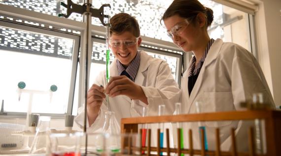 Two kids working with test tubes in science class.