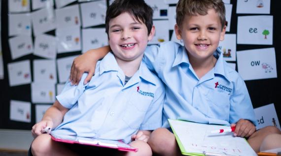 Two children doing maths on clipboards.