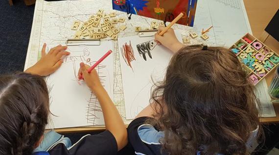 Young school kids drawing in books.