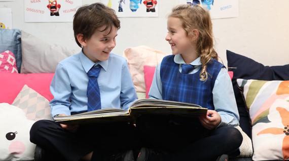 Two kids reading a picture book together.