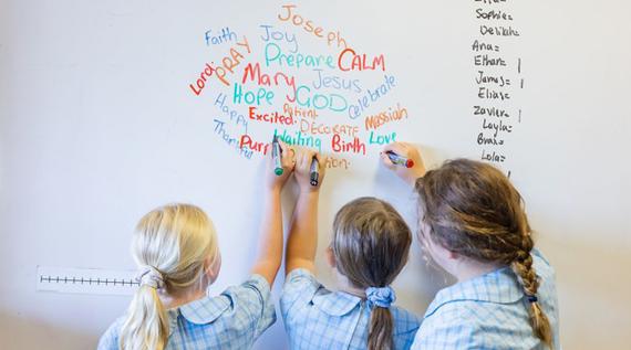 Kids writing words on a board like "hope" and "Jesus".