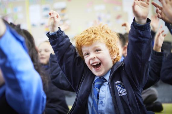 A young boy cheering in class.