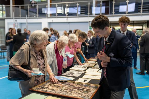 A student speaking with an older lady while looking at a photo of the St Pats site from years ago.