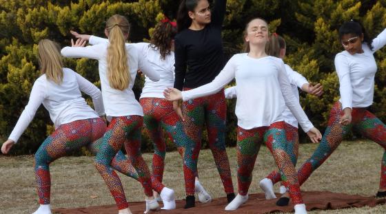 A group of Aboriginal girls doing a cultural dance outside.