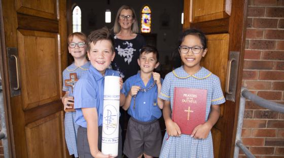 A group of young kids at their local Catholic Church with their teacher.