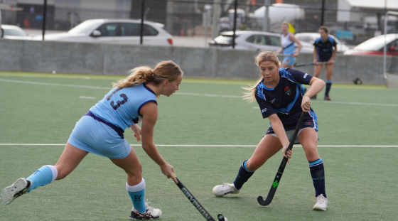 Two teenage girls playing hockey.