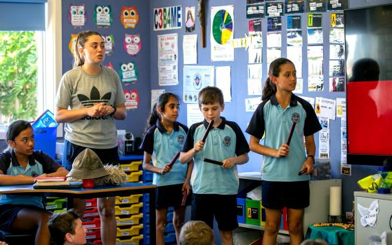 A group of young students using traditional Aboriginal instruments.