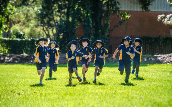 Kids running in a sprinting race on the school lawn.