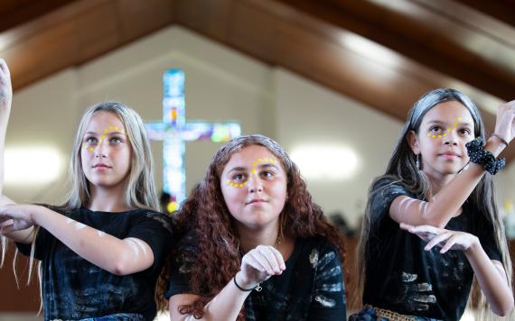 Three Aboriginal girls doing a cultural dance in the Catholic church.