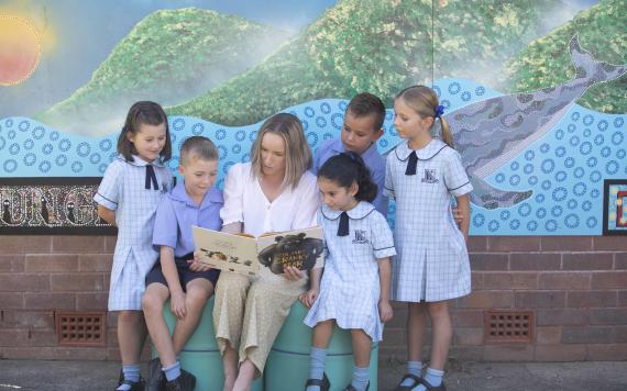 A teacher reading a picture book to young students.