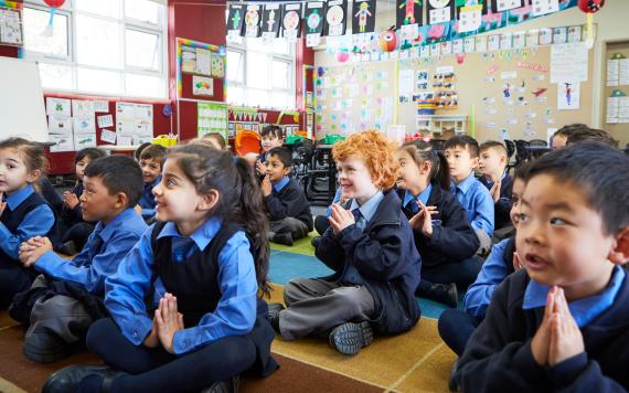 A group of young children praying in class.