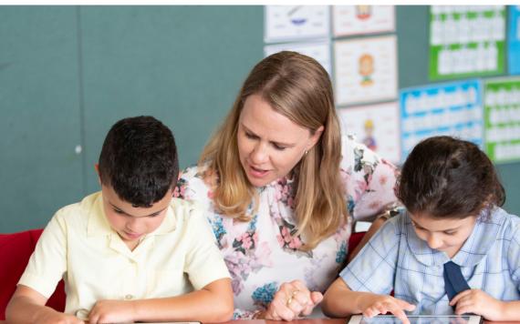 A teacher with two students learning on tablets.