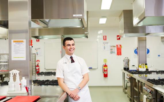 A student in a commercial kitchen learning how to work in that space.