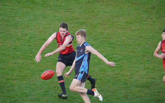 Two teenage boys playing Australian football.